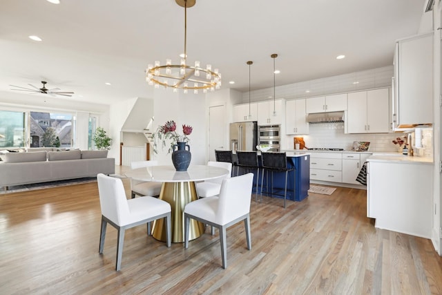 dining space with ceiling fan with notable chandelier, recessed lighting, and light wood-style flooring