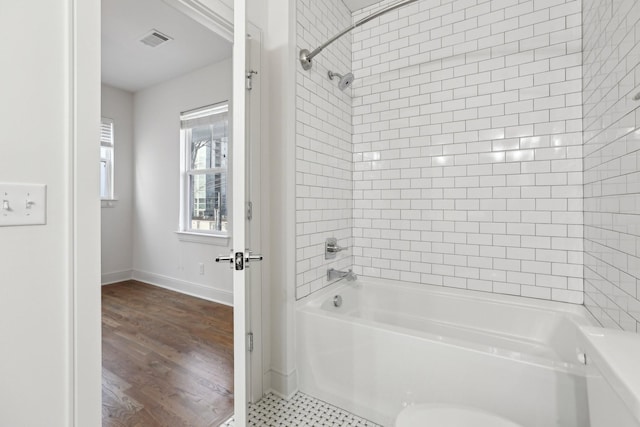 full bath featuring tub / shower combination, baseboards, wood finished floors, and visible vents
