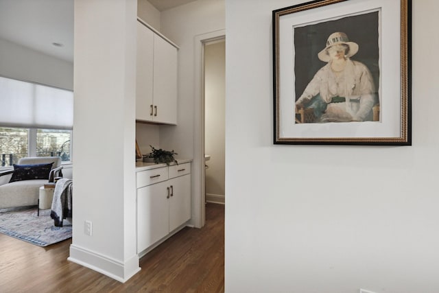 corridor with baseboards and dark wood-style flooring