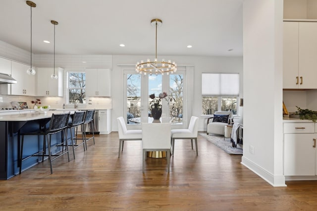 dining room with dark wood-style flooring, an inviting chandelier, a wealth of natural light, and recessed lighting
