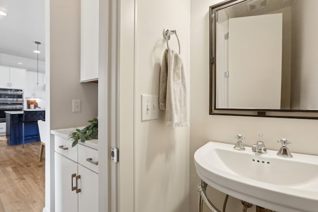 bathroom with recessed lighting, a sink, and wood finished floors