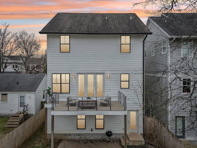 back of house with fence, a balcony, and roof with shingles