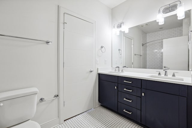 full bath featuring toilet, tile patterned floors, a tile shower, and a sink