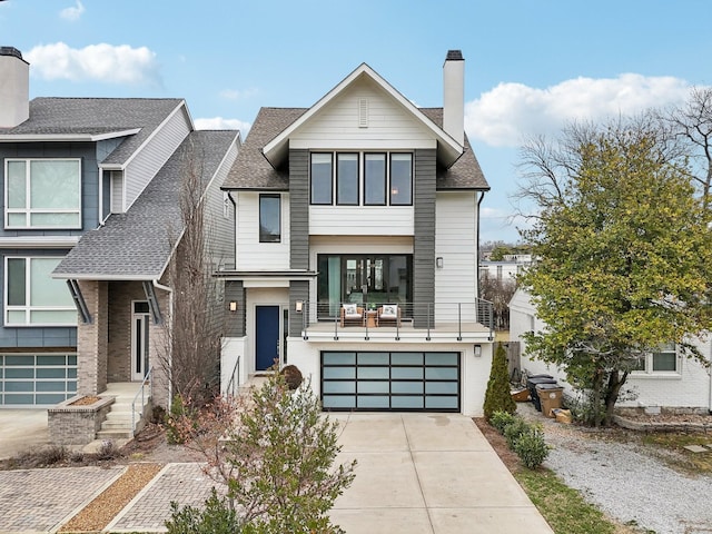 view of front of house featuring concrete driveway, a chimney, an attached garage, and roof with shingles
