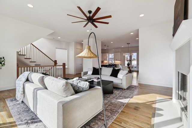 living room with stairs, a ceiling fan, baseboards, recessed lighting, and wood finished floors