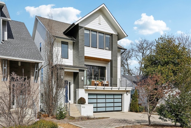 contemporary house with a garage, a balcony, driveway, and a shingled roof