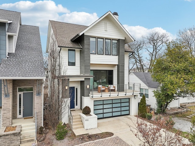 view of front of home featuring a garage, driveway, a chimney, and a shingled roof