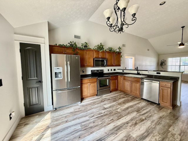 kitchen with visible vents, appliances with stainless steel finishes, dark countertops, brown cabinets, and a sink
