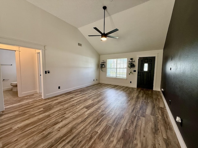 unfurnished living room featuring a ceiling fan, visible vents, wood finished floors, high vaulted ceiling, and baseboards
