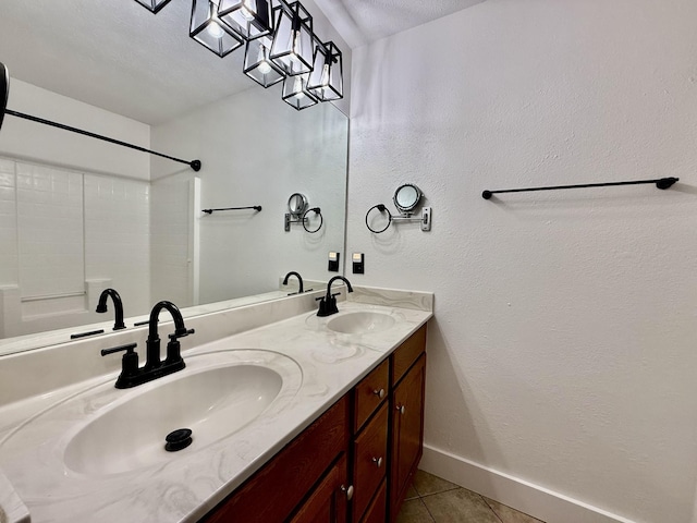 bathroom featuring baseboards, double vanity, tile patterned floors, and a sink