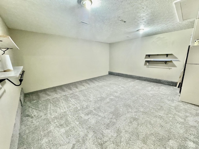 below grade area with freestanding refrigerator, a textured ceiling, and carpet flooring