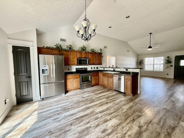 kitchen featuring a textured ceiling, appliances with stainless steel finishes, dark countertops, and light wood-type flooring