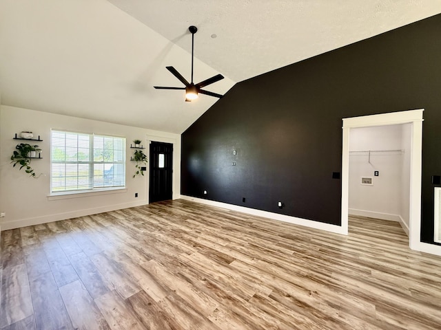 unfurnished living room with light wood-type flooring, a ceiling fan, baseboards, and lofted ceiling