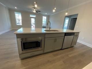 kitchen with stainless steel appliances, open floor plan, ornamental molding, and a sink