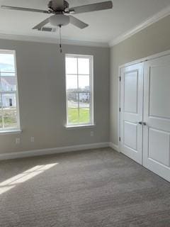 carpeted spare room featuring baseboards, ceiling fan, ornamental molding, and a wealth of natural light