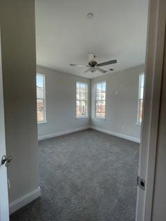 unfurnished room with baseboards, a ceiling fan, and dark colored carpet