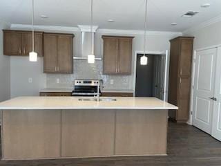 kitchen featuring a large island, crown molding, stainless steel electric range, a sink, and wall chimney exhaust hood