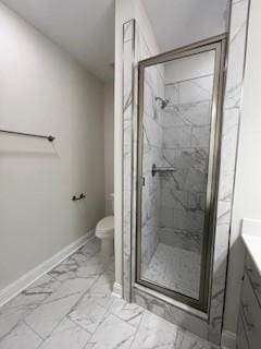 bathroom featuring vanity, marble finish floor, toilet, baseboards, and a marble finish shower