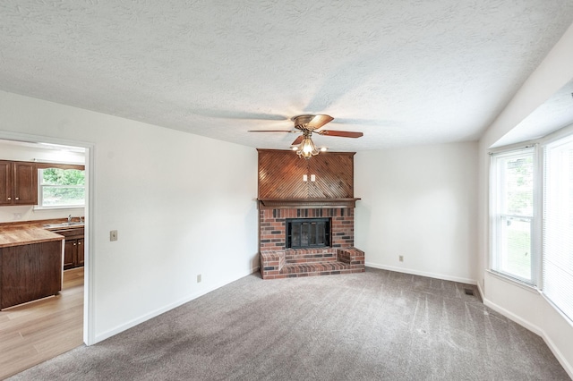 unfurnished living room featuring a healthy amount of sunlight, baseboards, a ceiling fan, and light colored carpet