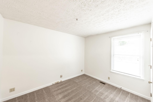 empty room featuring a textured ceiling, baseboards, visible vents, and carpet