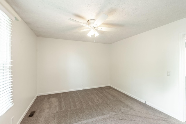 unfurnished room with visible vents, a ceiling fan, baseboards, and carpet floors