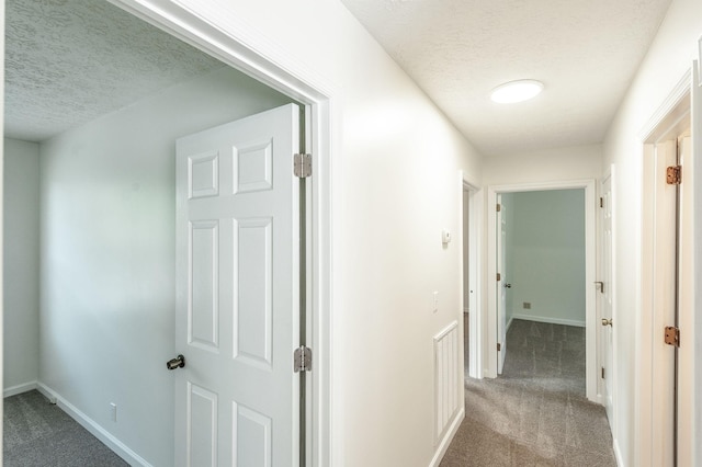 hall with carpet floors, a textured ceiling, and baseboards