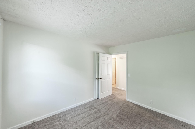 carpeted spare room featuring baseboards and a textured ceiling