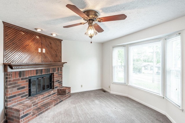 unfurnished living room with carpet floors, a textured ceiling, a brick fireplace, and baseboards