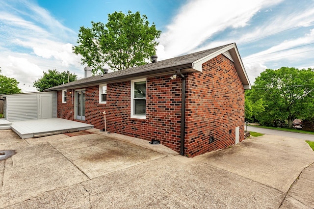 back of house with brick siding, a wooden deck, and a patio