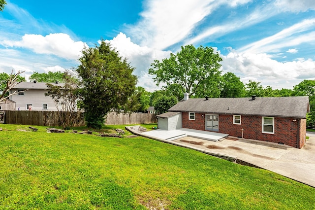 back of house with fence, brick siding, a chimney, a patio area, and a lawn