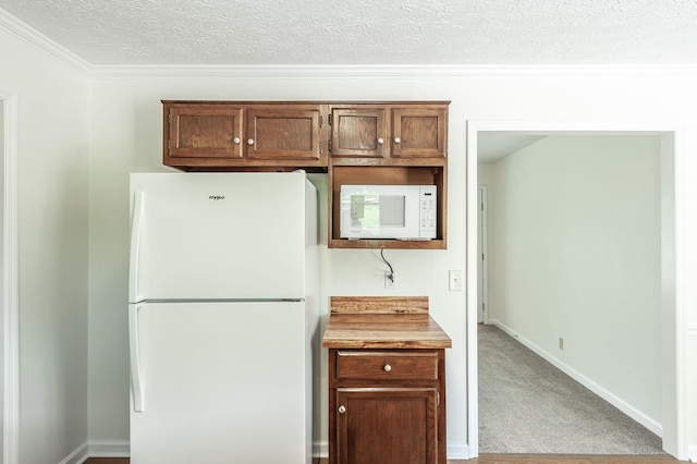 kitchen featuring ornamental molding, light carpet, white appliances, light countertops, and a textured ceiling