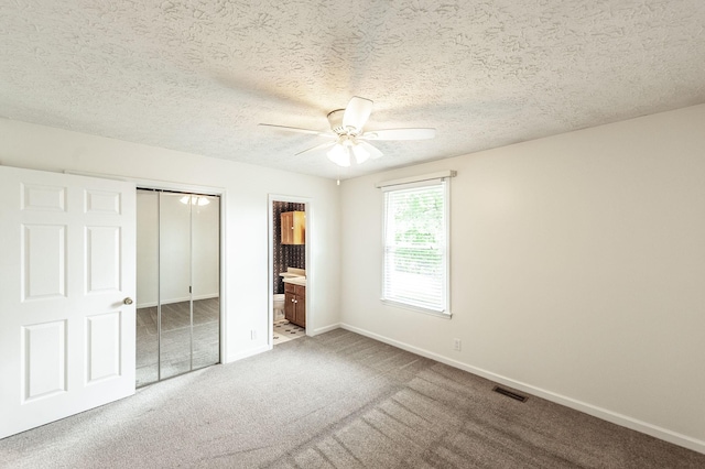 unfurnished bedroom with visible vents, carpet floors, baseboards, a closet, and ensuite bathroom