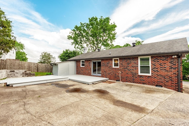 back of property with a chimney, brick siding, fence, a patio, and a shingled roof
