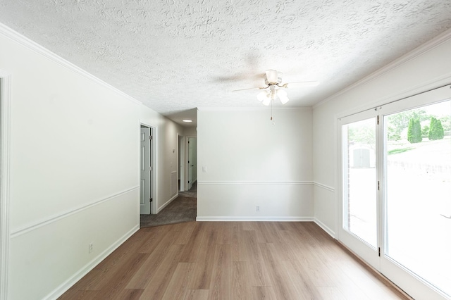 spare room featuring a textured ceiling, ceiling fan, ornamental molding, and light wood-type flooring