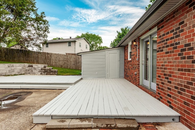 deck with a storage shed, fence, and an outbuilding