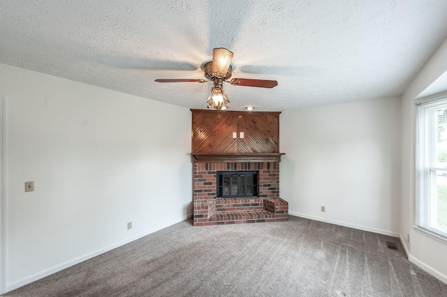 unfurnished living room with carpet flooring, ceiling fan, a brick fireplace, a textured ceiling, and visible vents