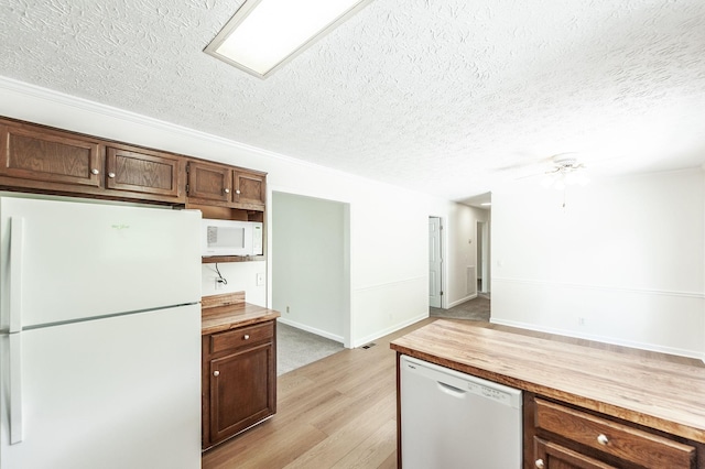 kitchen with wooden counters, white appliances, light wood-style floors, ceiling fan, and a textured ceiling