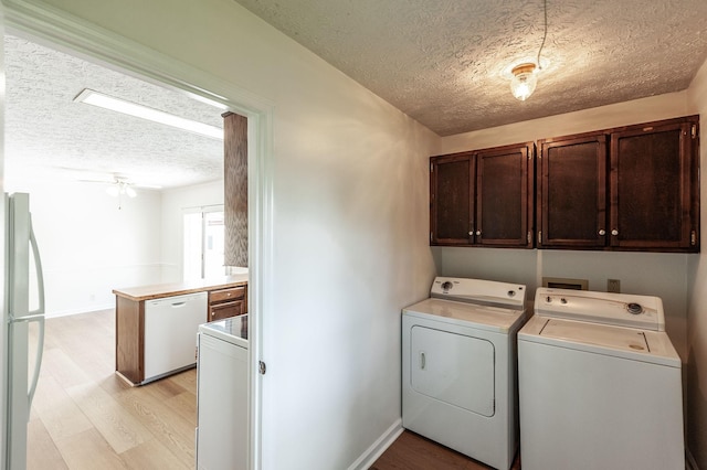 laundry room featuring cabinet space, a textured ceiling, washing machine and dryer, and light wood-type flooring