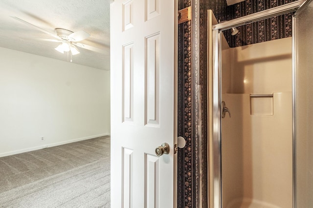 bathroom with a ceiling fan, baseboards, a shower stall, and a textured ceiling