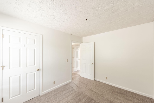 unfurnished bedroom featuring baseboards, carpet, and a textured ceiling