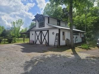 view of barn with fence and gravel driveway