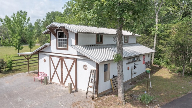 view of front of property featuring a garage, fence, metal roof, and a barn