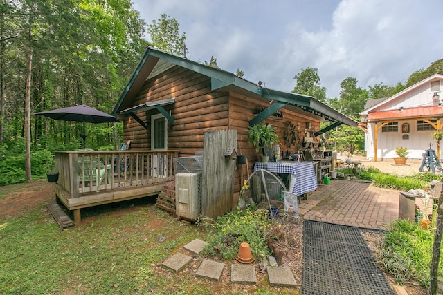rear view of property with a wooden deck and an outbuilding