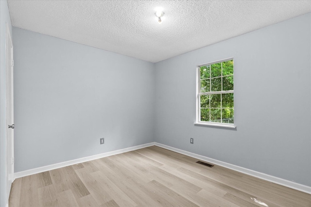 unfurnished room with baseboards, light wood finished floors, and a textured ceiling