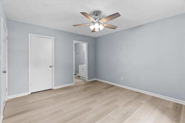 unfurnished bedroom featuring baseboards, ceiling fan, ensuite bathroom, and light wood-type flooring