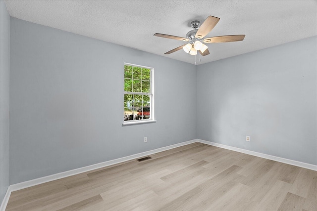 unfurnished room featuring a ceiling fan, a textured ceiling, visible vents, baseboards, and light wood-style flooring