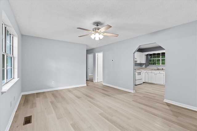 unfurnished living room featuring visible vents, a textured ceiling, light wood finished floors, and ceiling fan