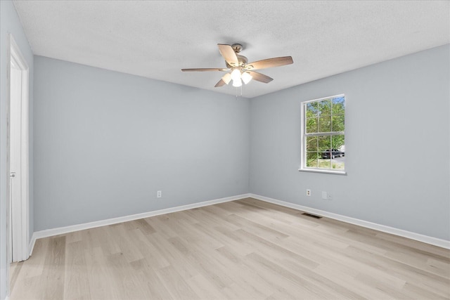 empty room with ceiling fan, light wood-style floors, a textured ceiling, baseboards, and visible vents