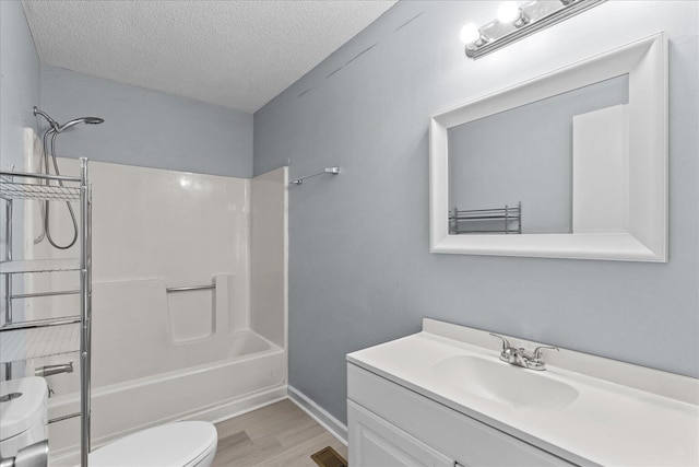 bathroom featuring bathtub / shower combination, vanity, toilet, a textured ceiling, and wood finished floors