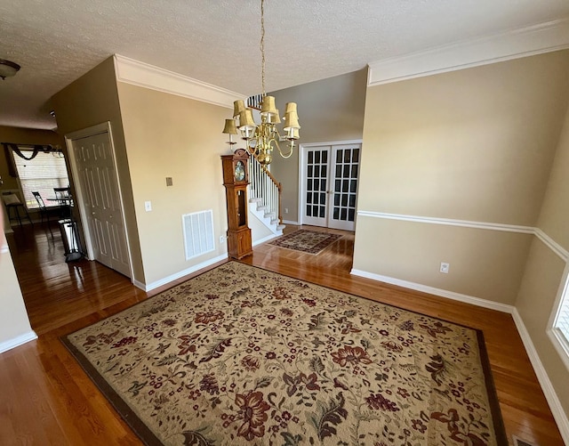 unfurnished dining area featuring baseboards, a textured ceiling, wood finished floors, and a notable chandelier